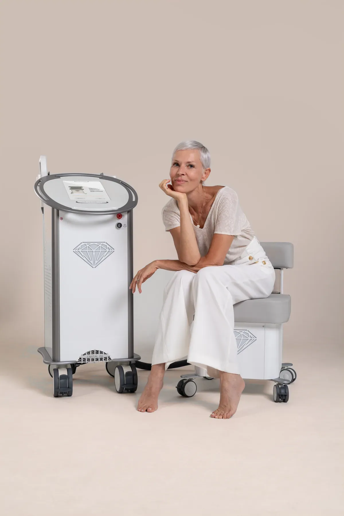 CRISTAL Fit® und CRISTAL reVive®: Gerät und Behandlungssessel, daneben eine sitzende Frau