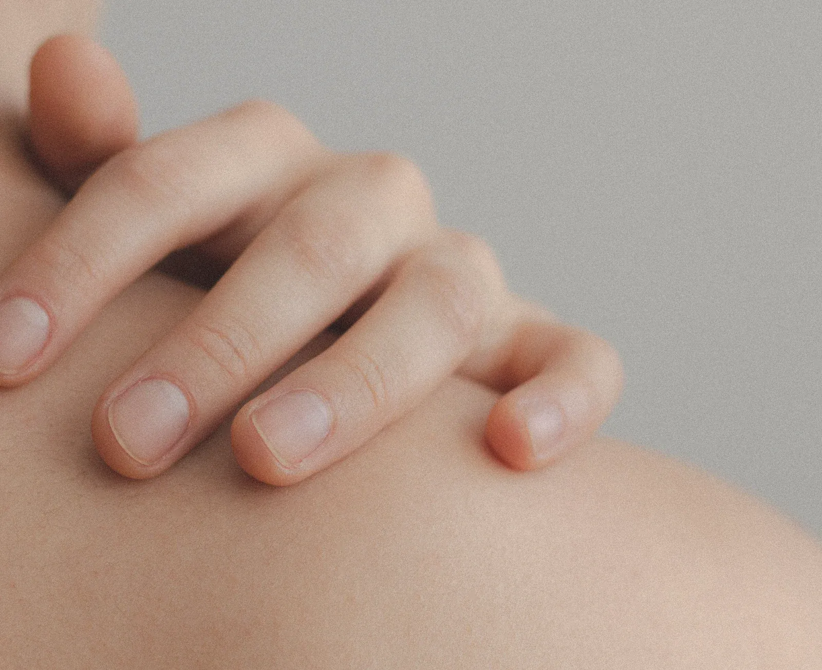 Hand auf der Haut einer Schulter in Nahaufnahme